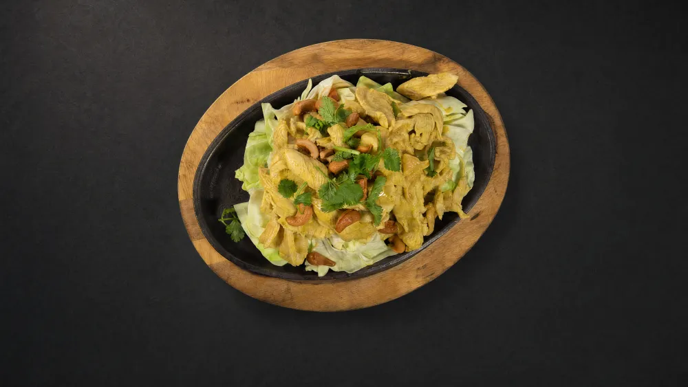 Thai Bistro cashew nut chicken with cilantro over cabbage on a sizzling platter